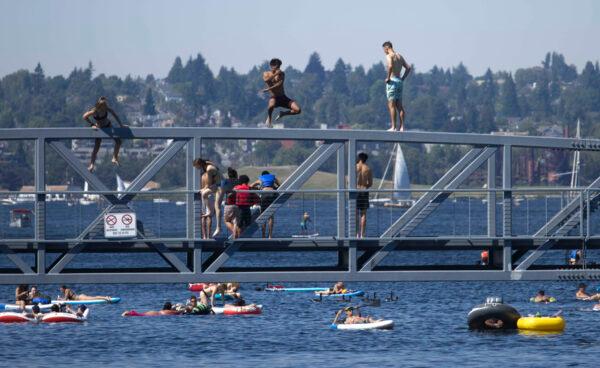 Two people jump from a pedestrian bridge into the water at Lake Union Park in Seattle during a heat wave, on June 27, 2021. (John Froschauer/AP Photo)