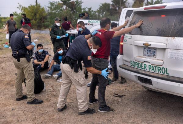 A transport officer searches illegal immigrants before bussing them to a processing center after they crossed the border from Mexico in La Joya, Texas, on April 13, 2021. (John Moore/Getty Images)
