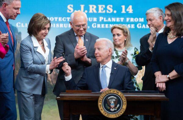 President Joe Biden hands a pen to House Nancy Pelosi (2nd L), alongside other members of the House, after signing a bill dealing with greenhouse gas emissions, in the Eisenhower Executive Office Building, in Washington, on June 30, 2021. (Saul Loeb/AFP/Getty Images)