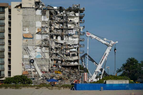 Workers peer up at the rubble pile at the partially collapsed AP Photo Champlain Towers South condo building in Surfside, Fla., on July 1, 2021. (Mark Humphrey/AP Photo)