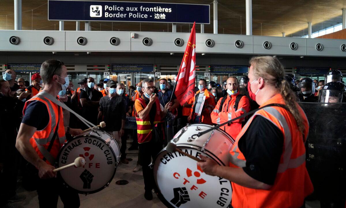 Protesters demonstrate in front of the passport control of Terminal 2E of Charles de Gaulle Airport in Paris on July 2, 2021. (Thanassis Stavrakis/AP Photo)
