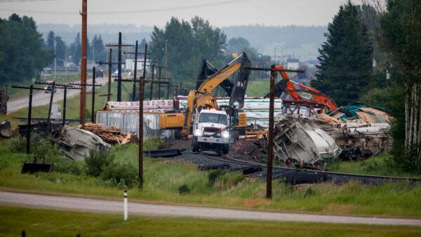 Crews work to clean up a spill after the derailment of a 20-car train carrying tar sands and lumber near Blackfalds, Alta., Canada, on July 3, 2021. (Jeff McIntosh/The Canadian Press via AP)