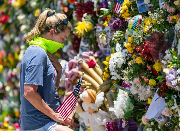 Miami Beach resident Tracey Lynne visits a makeshift memorial near the site of the collapsed Champlain Towers South Condo in Surfside, Fla., on July 3, 2021. (Matias J. Ocner/Miami Herald via AP)