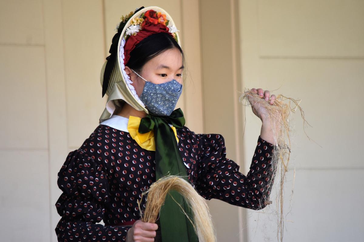 A costumed interpreter shares the process of turning natural fibers into summer clothing on the porch of MacKay House at Genesee Country Village & Museum. (Courtesy of Genesee Country Village & Museum)