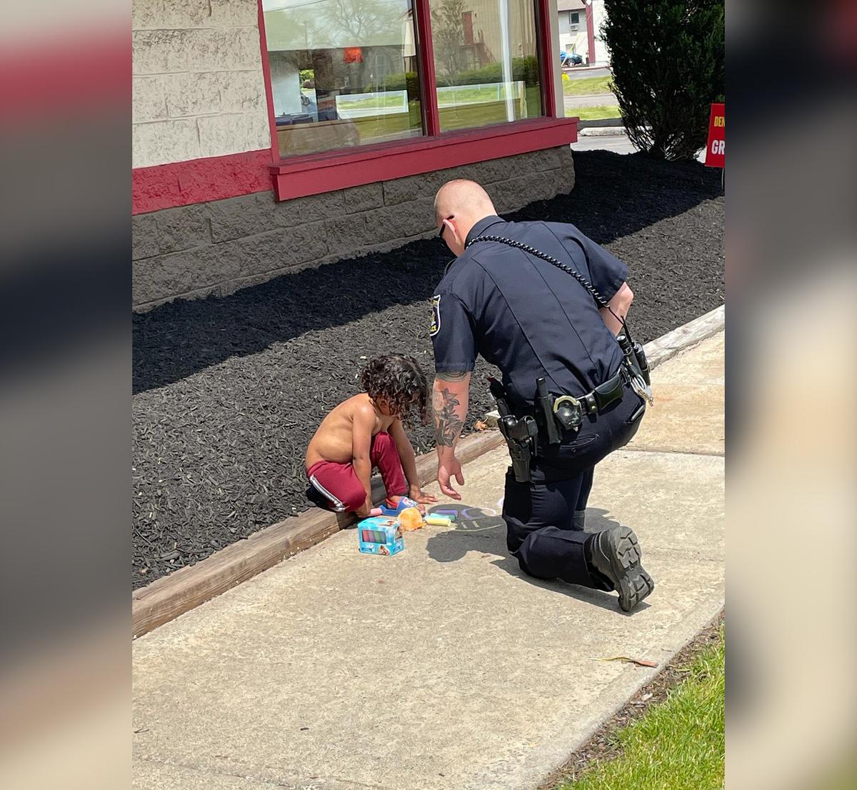 DeWitt police officer Tyler Smith kneels to comfort a 2-year-old outside a Denny's restaurant. (Courtesy of <a href="https://www.facebook.com/DeWitt-Police-Benevolent-Association-102274707996904">DeWitt Police Benevolent Association</a>)