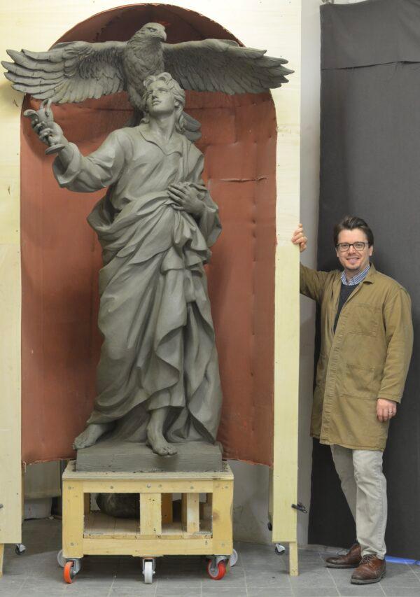 American sculptor Cody Swanson stands next to his sculpture of Saint John. The sculpture is one of the Four Evangelists he’s creating in clay, in preparation for it to be cast in plaster, for the Chapel of the Holy Cross, Jesuit High School, Tampa, Fla. (Courtesy of Cody Swanson)