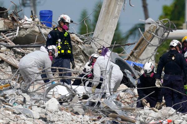 Rescue workers handle a tarp containing recovered remains at the site of the collapsed Champlain Towers South condo building in Surfside, Fla., on July 5, 2021. (Lynne Sladky/AP Photo)