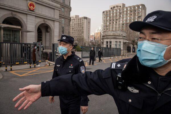 Police officers ask journalists to move away from outside the Beijing Second Intermediate People's Court in Beijing on March 22, 2021. (Nicolas Asfouri/AFP via Getty Images)
