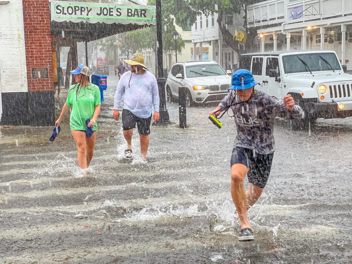 Pedestrians dash across the intersection of Greene and Duval streets as Tropical Storm Elsa passes Key West, Fla., on July 6, 2021. (Rob O'Neal/The Key West Citizen via AP)