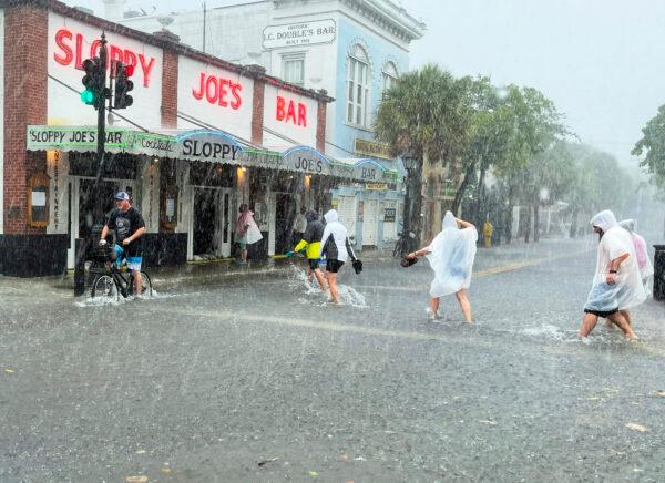 Determined visitors crossing a flooded Duval Street as heavy winds and rain pass over Key West, Fla., on July 6, 2021. (Rob O'Neal/The Key West Citizen via AP)