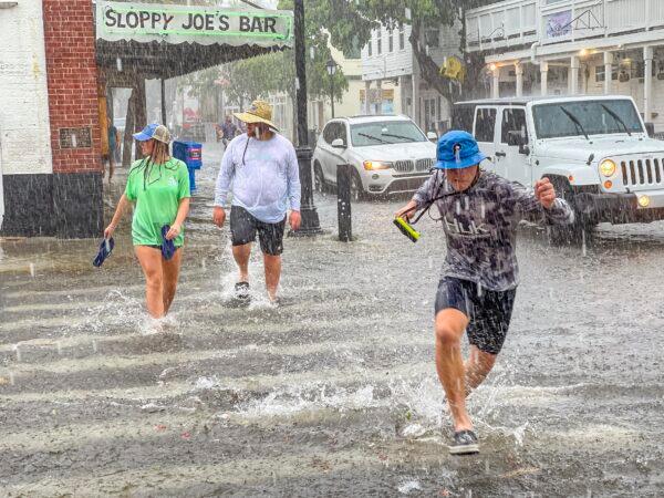 Pedestrians dash across the intersection of Greene and Duval streets as heavy winds and rain associated with Tropical Storm Elsa passes Key West, Fla., on July 6, 2021. (Rob O'Neal/The Key West Citizen via AP)