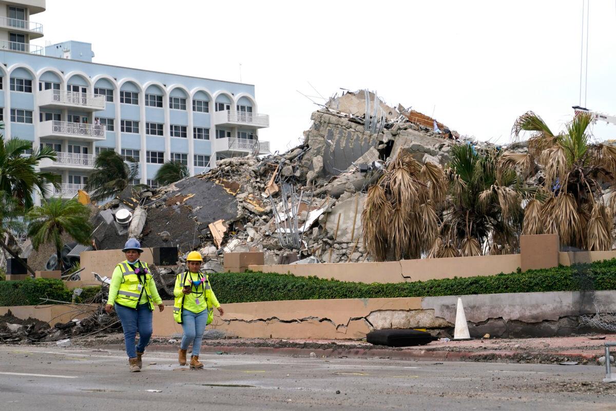 Workers walk past the collapsed and subsequently demolished Champlain Towers South condominium building in Surfside, Fla., on July 6, 2021. (Lynne Sladky/AP Photo)