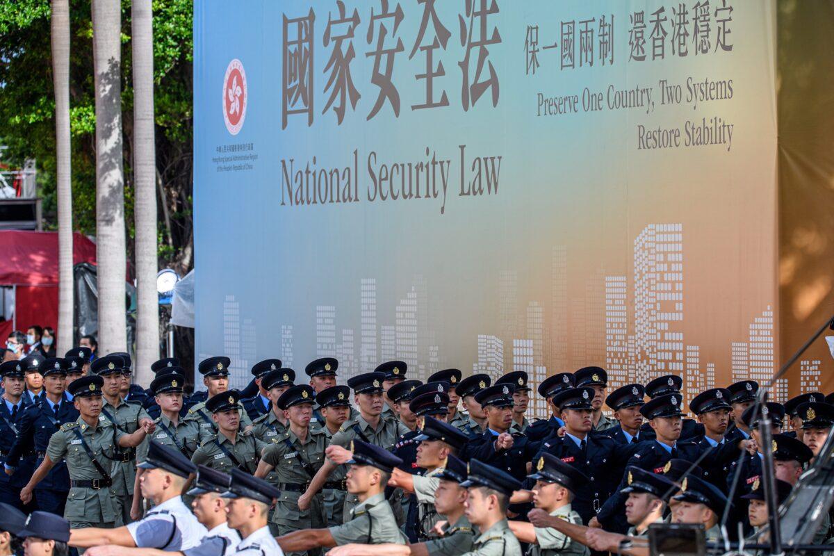 Attendees from various forces march next to a banner supporting the new national security law at the end of a flag-raising ceremony to mark the 23rd anniversary of Hong Kong's handover from Britain, in Hong Kong, on July 1, 2020. (Anthony Wallace/AFP via Getty Images)