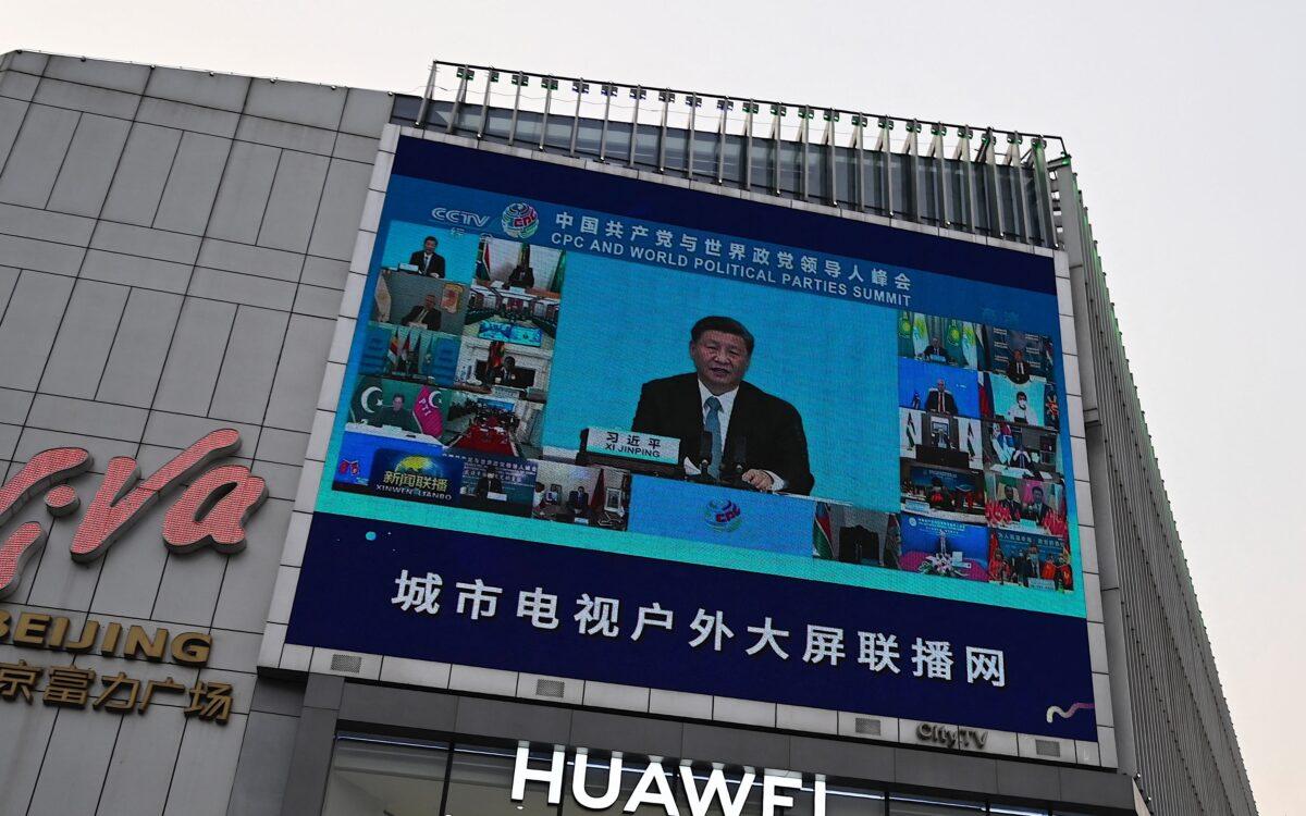 A screen shows news coverage of Chinese leader Xi Jinping delivering a speech during a Communist Party of China and World Political Parties summit, as people walk outside a shopping mall in Beijing on July 7, 2021. (Jade Gai/AFP via Getty Images)