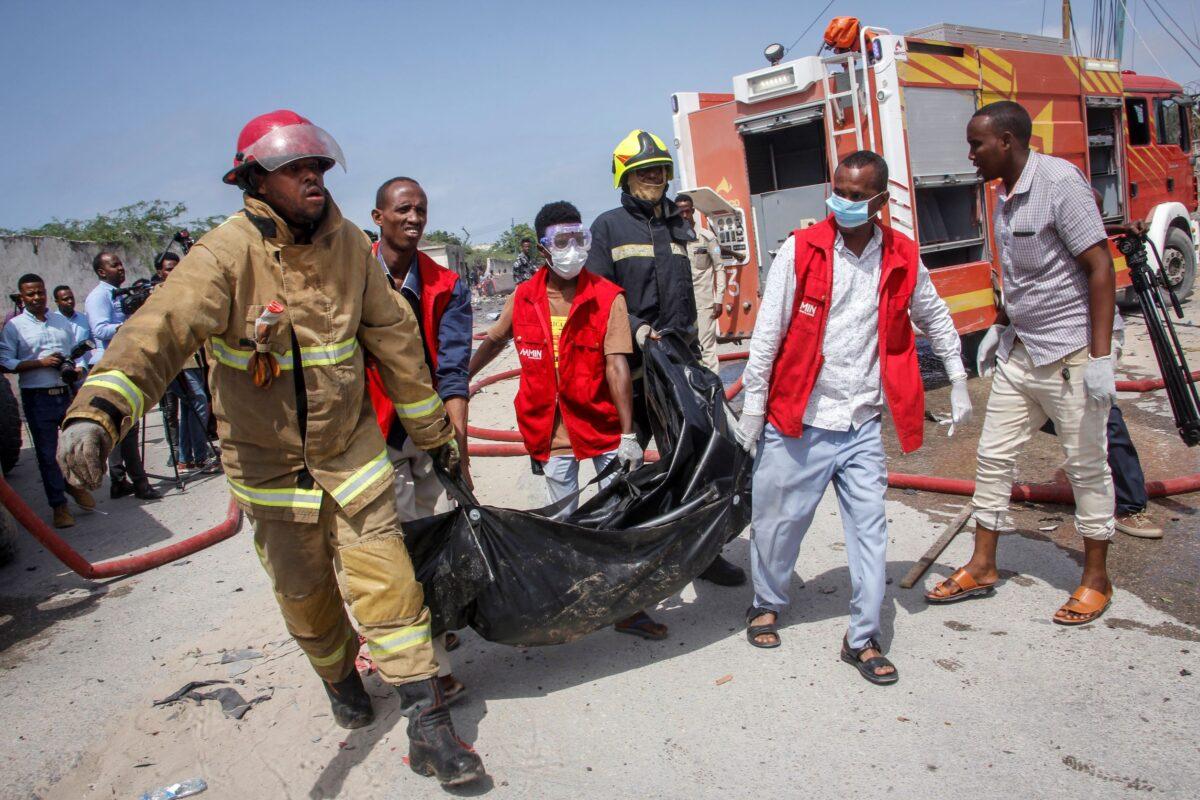 Medical workers carry the body of a civilian who was killed in a suicide car bomb attack that targeted the city's police commissioner in Mogadishu, Somalia, on July 10, 2021. (Farah Abdi Warsameh/AP Photo)