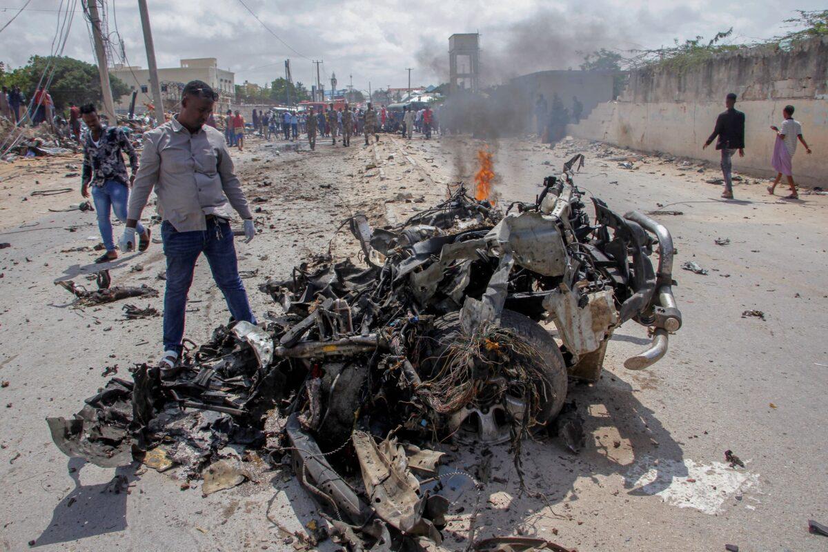 Security forces and civilians gather near the wreckage after a suicide car bomb attack that targeted the city's police commissioner in Mogadishu, Somalia, on July 10, 2021. (Farah Abdi Warsameh/AP Photo)
