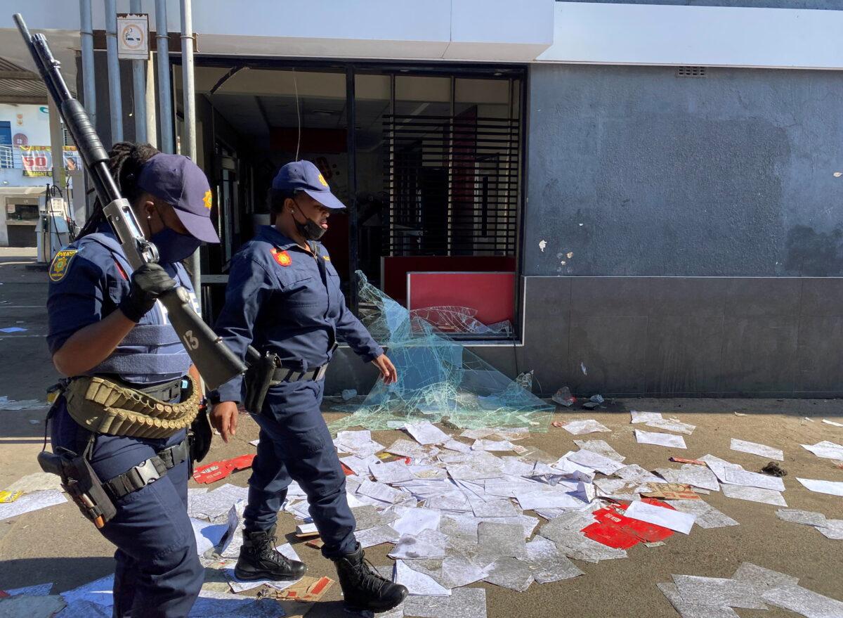 Police walk past a shop looted in protests in Durban, South Africa, on July 11, 2021. (Siyabonga Sishi/Reuters)
