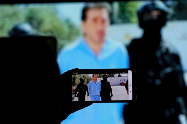 Bassem Awadallah, one of two former officials accused of helping Jordanian Prince Hamzah try to overthrow his half-brother King Abdullah II, appears on a mobile phone screen as he is escorted by security personnel at a state security court, in Amman, Jordan, on July 12, 2021. (Raad Adayleh/AP Photo)