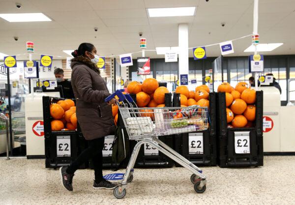 A woman wearing a mask pushes a shopping cart at a Tesco supermarket in Hatfield, United Kingdom, on Oct. 6, 2020. (Peter Cziborra/Reuters)