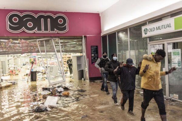 Suspected looters who surrendered to armed private security officers are marched outside, in a flooded mall in Vosloorus, on July 13, 2021. (Marco Longari/AFP via Getty Images)
