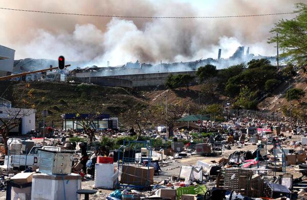 A factory burns in the background while empty boxes litter the foreground from looted goods being removed, on the outskirts of Durban, South Africa, on July 14, 2021. (AP Photo)
