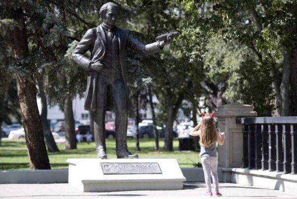 A little girl stops to look at a statue of John A. Macdonald in Victoria Park in Regina on Aug. 22, 2018. (The Canadian Press/Jonathan Hayward)