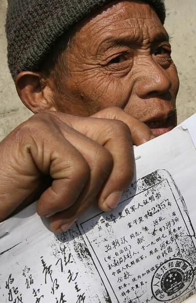 An elderly protester holds up his veteran certificate and his documents relating to a land dispute in Hebei Province, outside a petition office in Beijing, on March 7, 2006. (Mark Ralston/AFP via Getty Images)