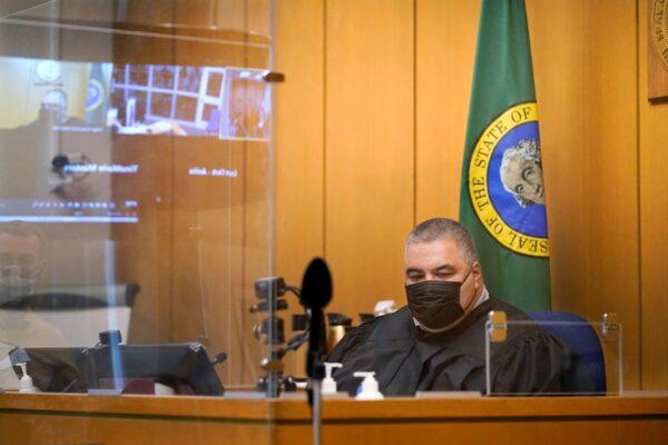 Judge Fa'amomoi Masaniai watches a video feed from a jail courtroom that is also reflected nearby during a hearing for NFL football player Richard Sherman at King County District Court, in Seattle, Wash., on July 15, 2021. (Elaine Thompson/AP Photo)