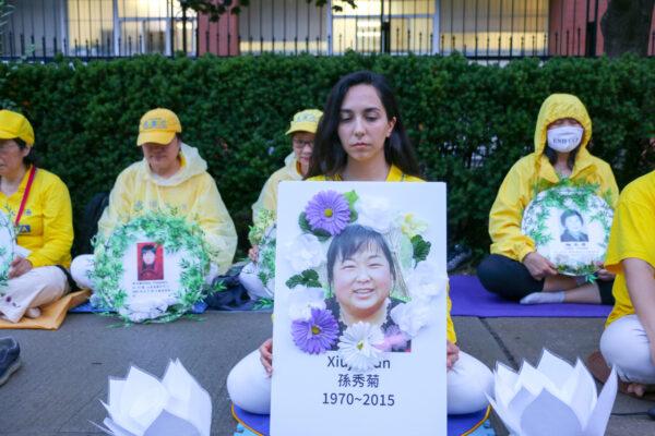 Elnaz Hajikhani holds a board memorializing a Falun Gong adherent who was persecuted to death in 2015 under the Chinese communist regime's persecution of Falun Gong, at a vigil in front of the Chinese Consulate in Toronto on July 15, 2021. Adherents of the Falun Gong spiritual faith held the vigil to commemorate 22 years of persecution and to call on the Chinese regime to end the persecution. (Andrew Chen/The Epoch Times)