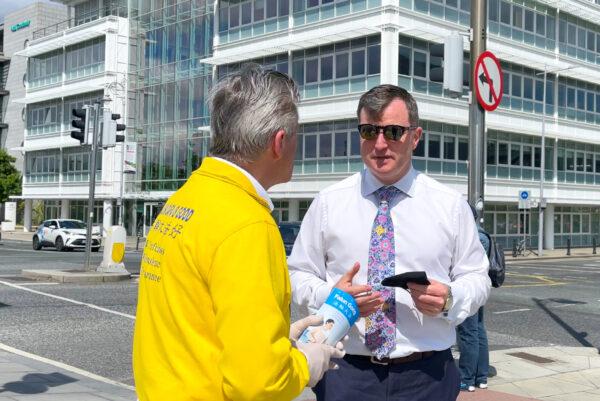 Senator Malcolm Byrne talking to a Falun Gong practitioner before a rally that marks the 22nd year of the persecution in China, in Dublin, Ireland on July 14, 2021. (Feng Yu/The Epoch Times)