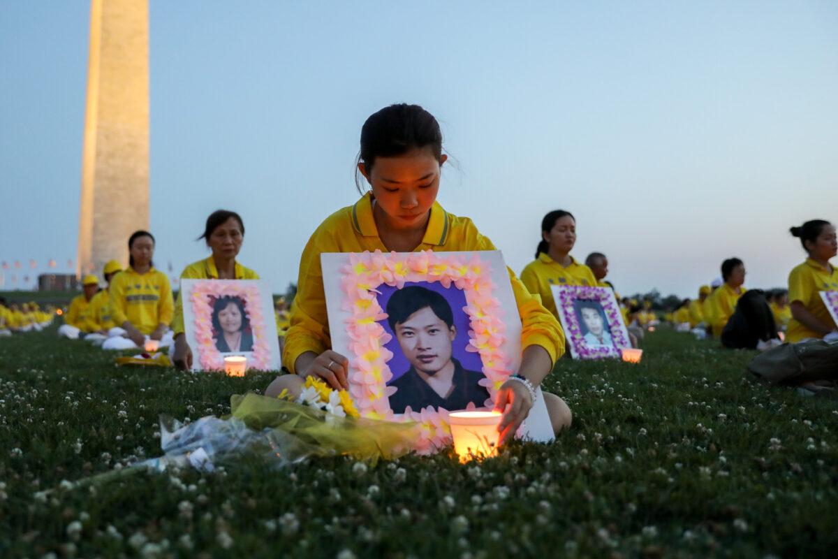 Xu Xinyang holds a picture of her father, who died as a result of the torture he endured in China because of his belief in Falun Gong, during a candlelight vigil remembering victims of the 22-year-long persecution in China, at the Washington Monument on July 16, 2021. (Samira Bouaou/The Epoch Times).