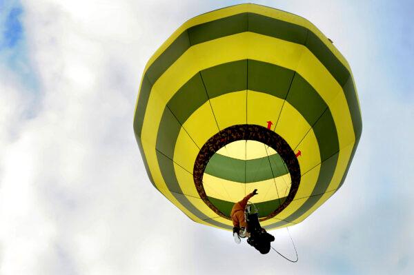 In a harness he created, Brian Boland, of Post Mills, Vt., takes off attached to a hot-air balloon with a passenger above Westshire Elementary School in West Fairlee, Vt., on Feb. 26, 2013. (Jennifer Hauck/The Valley News via AP)