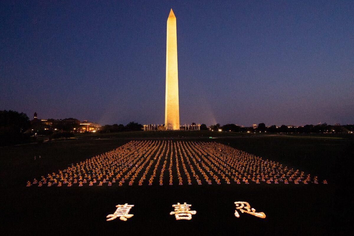 Falun Gong practitioners at candlelight vigil remembering victims of the 22 years of persecution in China at the Washington Monument on July 16, 2021. The characters for "Truthfulness, Compassion, Tolerance," the principles taught by the spiritual practice, appear at the front. (Edward Dai/The Epoch Times).