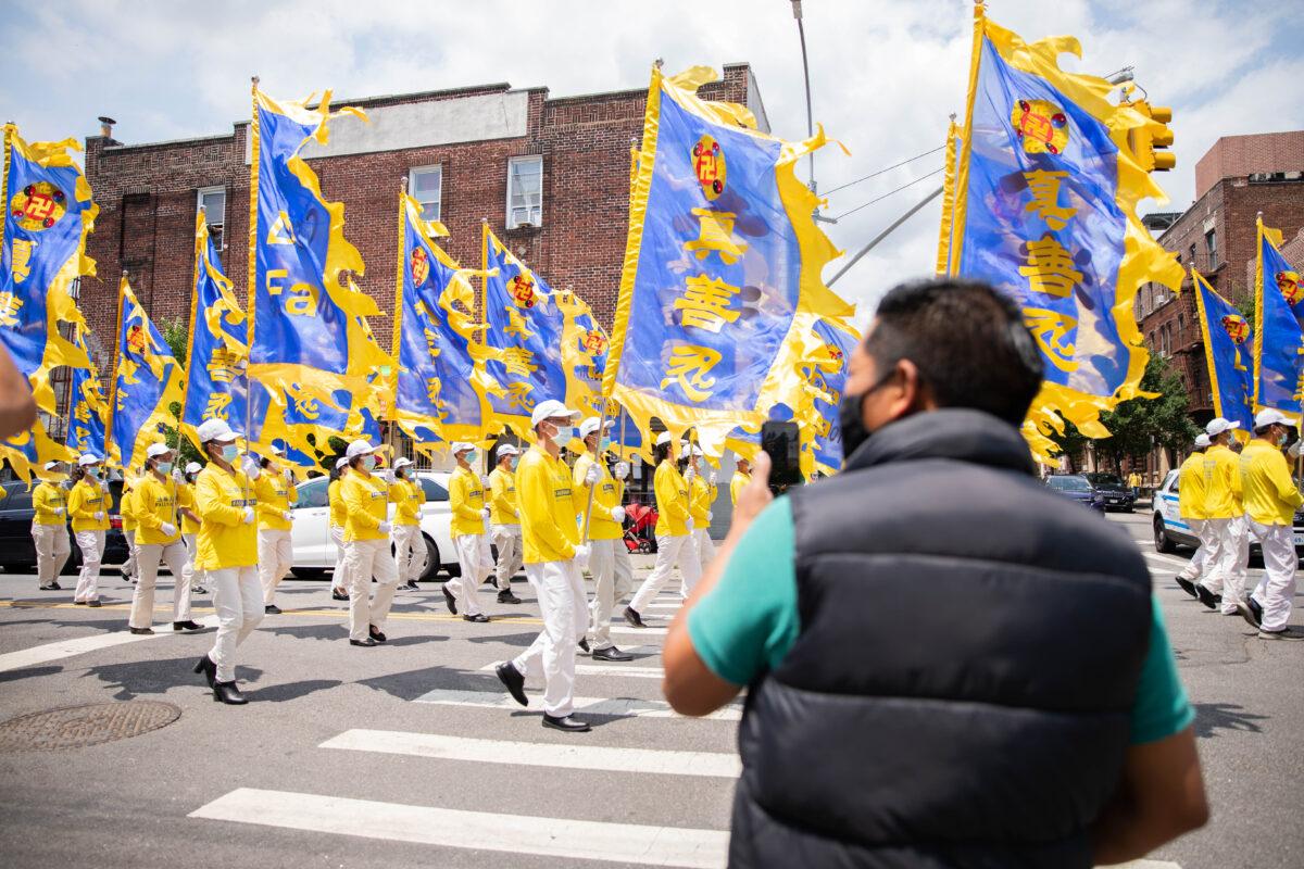 Bystanders watch a parade by practitioners of the spiritual discipline Falun Gong in Brooklyn, N.Y., on July 18, 2021. (Chung I Ho/The Epoch Times)