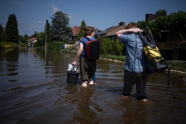 Residents return to their homes with cleaning materials in the town of Brommelen, Netherlands, on July 17, 2021. (Bram Janssen/AP Photo)