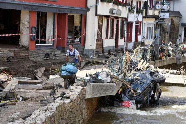 A man helps with the cleanup by carrying rubbish and debris after heavy rain and flooding along the Erft in Bad Münstereifel, Germany, on July 17, 2021. (Roberto Pfeil/dpa via AP)