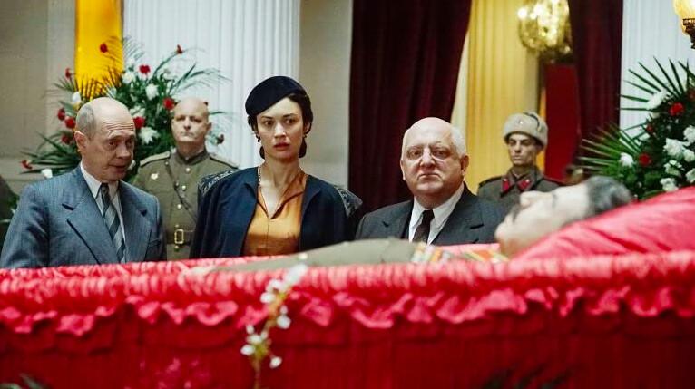 (L–R) Nikita Khrushchev (Steve Buscemi), Maria Veniaminovna Yudina (Olga Kurylenko), and Lavrentiy Beria (Simon Russell Beale) view Stalin’s body, in "The Death of Stalin." (Entertainment One Films)