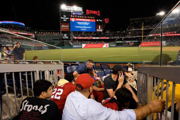Spectators take cover during a stoppage in play due to an incident near the ballpark during the sixth inning of a baseball game between the Washington Nationals and the San Diego Padres, in Washington, on July 17, 2021. (Nick Wass/AP Photo)