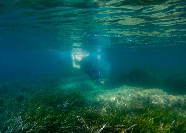 Cyprus Antiquities Department official Yiannis Violaris dives over submerged stone remains of the ancient harbor next of Amathus ancient city, in the eastern Mediterranean island of Cyprus, on July 1, 2021. (Petros Karadjias/AP Photo)