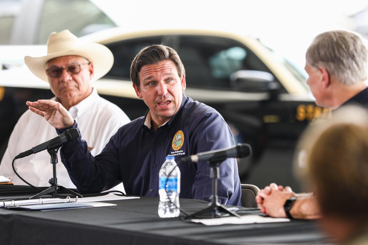 Florida Gov. Ron DeSantis speaks at a border meeting, while Val Verde County Sheriff Joe Frank Martinez (L) and Texas Gov. Greg Abbott (R) look on, in Del Rio, Texas, on July 18, 2021. (Charlotte Cuthbertson/The Epoch Times)