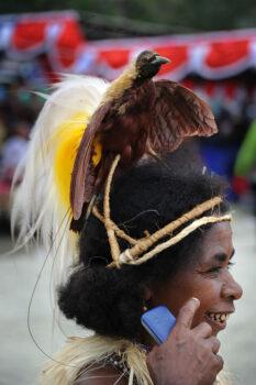 Photo taken on June 20, 2011, shows a Papuan tribeswoman wearing a crown of preserved plumage of a Bird of Paradise holding a mobile phone during the Lake Sentani festival in the Jayapura district of the eastern Indonesian province of Papua. (Romeo Gacad/AFP via Getty Images)