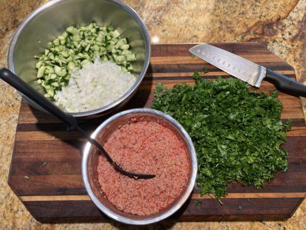 Tabbouleh assembly: chopped cucumbers and onions, lots of parsley, and fluffy, tomato-red bulgur. (Ari LeVaux)