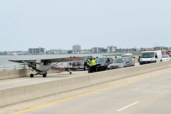 Emergency responders talk with Landon Lucas after he made an emergency landing on the Route 52 causeway connecting Ocean City and Somers Point, N.J., on July 19, 2021. (Matthew Strabuk/The Press of Atlantic City via AP)