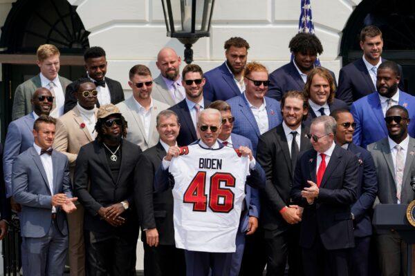 President Joe Biden, surrounded by members of the Tampa Bay Buccaneers, poses for a photo holding a jersey during a ceremony on the South Lawn of the White House, where Biden honored the Super Bowl Champion Tampa Bay Buccaneers for their Super Bowl LV victory, in Washington, on July 20, 2021. (Andrew Harnik/AP Photo)