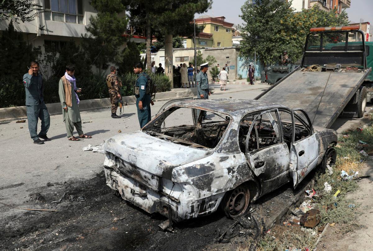 Security personnel inspect a damaged vehicle where rockets were fired from in Kabul, Afghanistan, on July 20, 2021. (Rahmat Gul/AP Photo)
