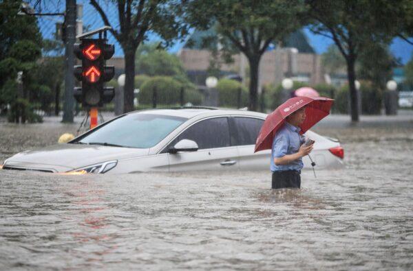 A man is wading past a submerged car along a flooded street following heavy rains in Zhengzhou in central China's Henan Province on July 20, 2021. (STR/AFP via Getty Images)