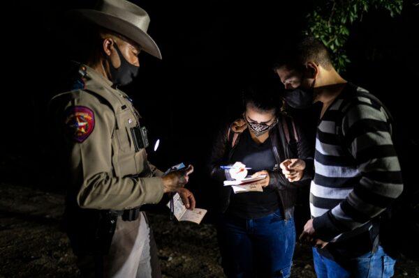 A Texas State Trooper takes down information from illegal immigrants after they arrive in Texas near the border between Mexico and the United States in Del Rio, Texas on May 16, 2021. (Sergio Flores/AFP via Getty Images)