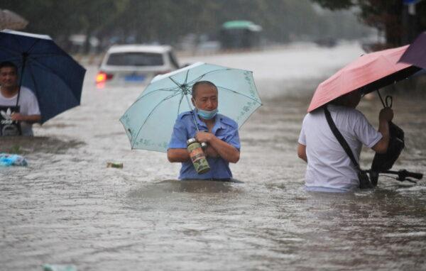 Residents wade through floodwaters on a flooded road in Zhengzhou, Henan province, China, on July 20, 2021. (China Daily via Reuters)