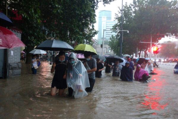 People move through flood water after a heavy downpour in Zhengzhou city, central China's Henan Province on July 20, 2021. (Chinatopix Via AP)
