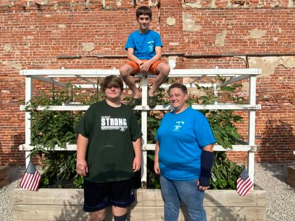 From left, Troop 340 Scout Zach Ranson, Troop 340 Scout Jayden Brown (top) and Adult Mentor Jill Waltman stand in front of one several raised beds growing in the Auburn (Illinois) Community Garden, which was established in the spring of 2020 by Troop 340. Harvest from the garden is donated to a food pantry and a “breadline” as well as offered to the public. (Tamara Browning)